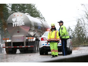 Trucks and other vehicles pass a police checkpoint on the partly reopened Highway 7 between Mission and Agassiz on November 18, 2021.