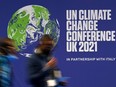Delegates pass a sign for the UN Climate Change Comference UK 2021, during the COP26 summit in Glasgow, Scotland, Tuesday, Nov. 2, 2021.