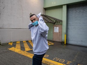 Mohammad Movassaghi tries to hide his face with a copy of his release order as he leaves Vancouver Police Department jail in Vancouver on Sunday, January 31, 2021.