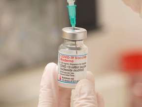 Health care worker fills up a syringe with a dose of Moderna’s COVID-19 vaccine for a booster shot.