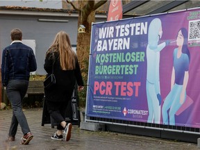People walk past a sign of a coronavirus disease (COVID-19) test centre amid the COVID-19 pandemic in Furstenfeldbruck, Germany, November 27, 2021.