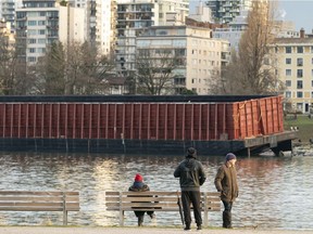 Curious onlookers gather to watch a large barge that sits on the rocks at Sunset Beach.