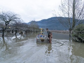 Ernest Romanchik pushes a boat with supplies for his and his landlord's home in Abbotsford, BC, November, 22, 2021.