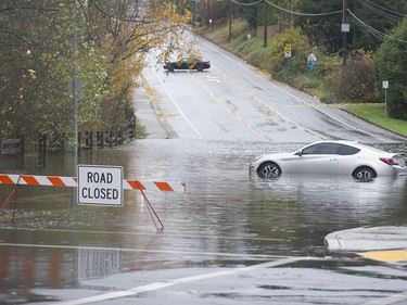 A car sits in a pool of water in the closed intersection of Old Yale Road and Mitchell Street in Abbotsford on Nov. 15, 2021. Two days of rains have flooded, closed or washed out many roads in the Lower Mainland and the Fraser Valley.