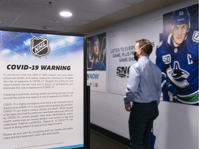 A man walks past a COVID-19 warning sign after entering Rogers Arena prior to NHL hockey action between the Vancouver Canucks and the Toronto Maple Leafs on April 17, 2021 in Vancouver, Canada.