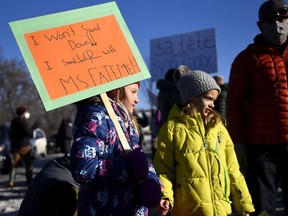 Grade 3 students Zoe Meldrum (left) and Lola Jo Advokaat, whose teacher Fatemeh Anvari was removed from her position because she wears a hijab, participate in a rally against Quebec's Bill 21, in Chelsea, Que., on Dec. 14, 2021. Bill 21 bans public sector workers who are considered to be in positions of authority, including teachers, from wearing religious symbols while working.