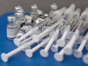 Syringes and vials of Pfizer-BioNTech COVID-19 vaccine are seen on a work surface during a drive through clinic at St. Lawrence College in Kingston, Ont., Saturday, Dec. 18, 2021.