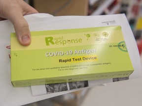 A man displays his COVID-19 rapid test kit after receiving it at a pharmacy in Montreal, Monday, Dec. 20, 2021, as the COVID-19 pandemic continues in Canada and around the world.