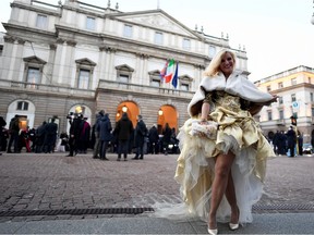 A guest poses in front of the theatre before the opening night of the La Scala opera house in Milan, Italy, December 7, 2021.