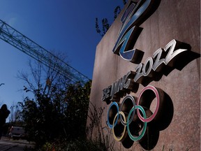 FILE PHOTO: A woman walks past the Beijing 2022 logo that is seen outside the headquarters of the Beijing Organising Committee for the 2022 Olympic and Paralympic Winter Games in Shougang Park, the site of a former steel mill, in Beijing, China, November 10, 2021. REUTERS/Thomas Peter/File Photo