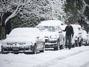 A man clears snow from his car in North Vancouver on Dec. 25, 2021.