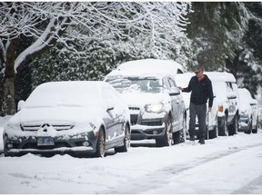 La neige a accueilli les gens dans le matin de Noël du Lower Mainland le samedi 25 décembre 2021, créant un Noël blanc.  Sur la photo, un homme déblaye la neige de sa voiture à North Vancouver, en Colombie-Britannique.