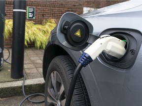 An electric vehicle is plugged into a charging station outside a bank in Burnaby, Nov. 20, 2021.