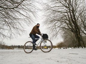 A man bicycles in the snow at Trout Lake in Vancouver on Dec. 27.