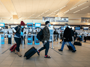 Travelers carry luggage to their flights at the Edmonton International airport on December 2, 2021.