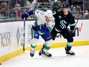 Bo Horvat of the Vancouver Canucks and Will Borgen #3 of the Seattle Kraken fight for a loose puck during the first period at Climate Pledge Arena on Jan. 1 in Seattle.