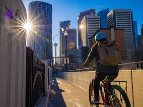 A cyclist crosses the Centre Street Bridge with downtown Calgary office towers as a backdrop on Wednesday, November 24, 2021.