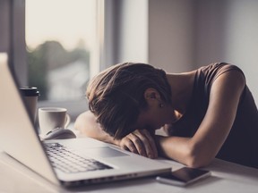 Tired businesswoman in the office with laptop and coffee