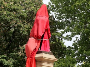 A statue of Canada's first Prime Minister, John A. Macdonald, is shrouded by Indigenous supporters at City Park in Kingston on Friday June 11, 2021.