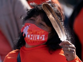 A woman holds an eagle feather as she listens to speakers during National Day for Truth and Reconciliation ceremonies on Parliament hill, Thursday, September 30, 2021 in Ottawa