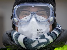 A doctor wears PPE, including an N95 respirator at a drive through COVID-19 vaccine clinic in Ontario.