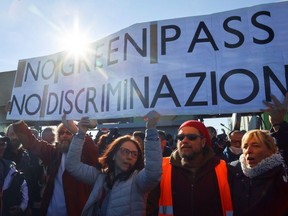 People carry banners as they participate in a protest against the implementation of the COVID-19 health pass, the Green Pass, in the workplace as they gather outside the entrance of the major port of Trieste, Italy, October 15, 2021.