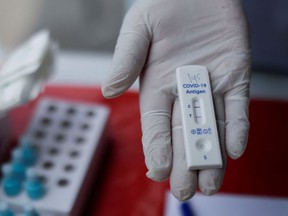 A health-care worker holds a positive antigen test for COVID-19.