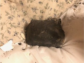 A meteorite rests on a bed inside a residential building in Golden, B.C., in an undated handout photo. Ruth Hamilton says she was sound asleep on Oct. 4 when she was awakened by her dog barking, the sound of a crash through her ceiling and the feeling of debris on her face.