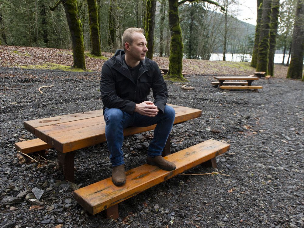 Chilliwack resident Trevor Carne sits on a picnic table surrounded by flood debris at the Maple Bay campground at Cultus Lake.