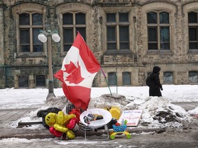 A Canadian flag is propped up in a small snowbank near the Parliament Buildings in Ottawa where trucks formed a blockade of streets amid a demonstration protesting vaccine mandates on Feb. 16.