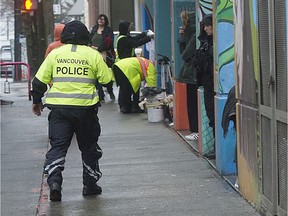 A Vancouver police officer walks in the 300-block Columbia Street on the Downtown Eastside on Nov. 25, 2021.