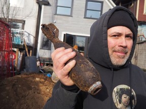 Curt Topal with a three inch mortar shell he found while digging underneath his house in Vancouver. He posed for the photo while waiting for police to arrive, not realizing the potential danger, having already hit the shell with a shovel … twice.