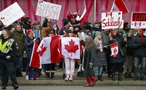 Protesters hold signs as they gather on Burrard Street on February 5, 2022.