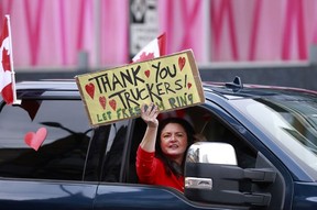 A protester holds a sign as she walks down Burrard Street in Vancouver on February 5, 2022.
