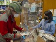 Chia-Ning Chen serves Chris Haddock, a regular customer at The Smoke Shop (also known as The Tuck Shop), Chen's business in the Granville Island Market in Vancouver on Feb. 16, 2022.  Chen has been told her lease will not be renewed and she must leave the market within two months.