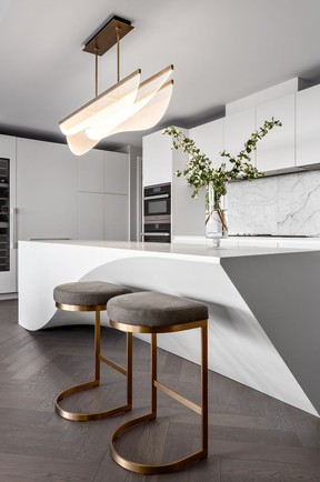 A curvy Nyra Linear pendant from Tech Lighting, and Restoration Hardware 1960s Rome backless counter stools, complement the shape of the kitchen island.