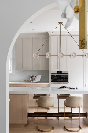 This Kitsilano kitchen combines stately touches such as arches and marble cladding with modern amenities, including a wall of cabinets concealing charging areas for laptops and other gadgets.