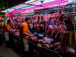 A stall worker (C) cuts pork for a customer (L) at the Wan Chai wet market in Hong Kong on January 5, 2019. (Photo by ISAAC LAWRENCE/AFP via Getty Images)