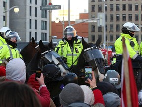 Police officers on horseback wade through a demonstration of anti-vaccine-mandate truckers and supporters in Ottawa on Friday.