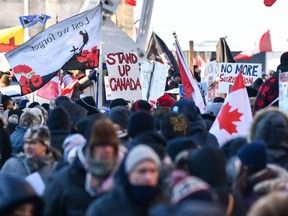 Protesters near Parliament Hill hold signs condemning the vaccine mandates imposed by Prime Minister Justin Trudeau, in Ottawa, Saturday, Feb. 5, 2022.