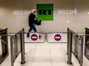 This file photo taken on June 8, 2018 shows a man as he walks past a control post of the Russia Today (RT) TV company in Moscow. - EU to ban Russian state media RT and Sputnik announced European Commission President Ursula von der Leyen on Feb. 27, 2022.