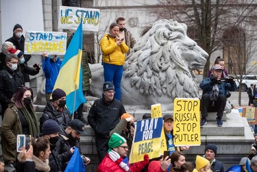 People hold signs and flags as thousands gather for a rally in support of the people of Ukraine, in Vancouver, on Saturday, February 26, 2022.