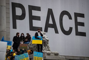 People hold signs and flags as thousands gather for a rally in support of the people of Ukraine, in Vancouver, on Saturday, February 26, 2022.