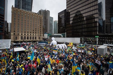 People hold signs and flags as thousands gather for a rally in support of the people of Ukraine, in Vancouver, on Saturday, February 26, 2022.