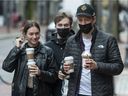 Les gens portent des tasses à café jetables à l'extérieur d'un Starbucks sur la rue Water à Vancouver le 9 février.