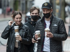 People with disposable coffee cups outside a Starbucks coffee shop on Water Street in Vancouver, BC Wednesday , February 9, 2022.