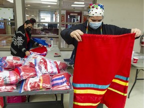 Sweet Grass Sisters Healing Society COO Jamie Smallboy, right, inspects ribbon skirts that will be distributed to family members of Indigenous murdered and missing women, at the Strathcona Community Centre in Vancouver on Feb. 12.