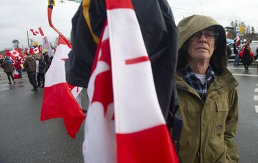 A man shoves his flag into the lens of the photographer as hundreds of people protest mask and vaccine mandates at 176th and 8th Avenue in Surrey, B.C., Saturday, Feb. 19, 2022. The Pacific Highway border crossing was closed by police due to the size of the protest.