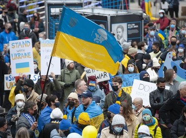 People hold signs and flags as thousands gather for a rally in support of the people of Ukraine, in Vancouver, on Saturday, February 26, 2022.