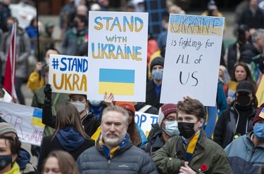 People hold signs and flags as thousands gather for a rally in support of the people of Ukraine, in Vancouver, on Saturday, February 26, 2022.